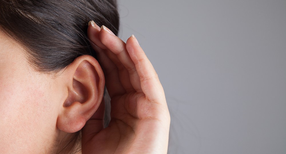 womans ear listening with hand on ear